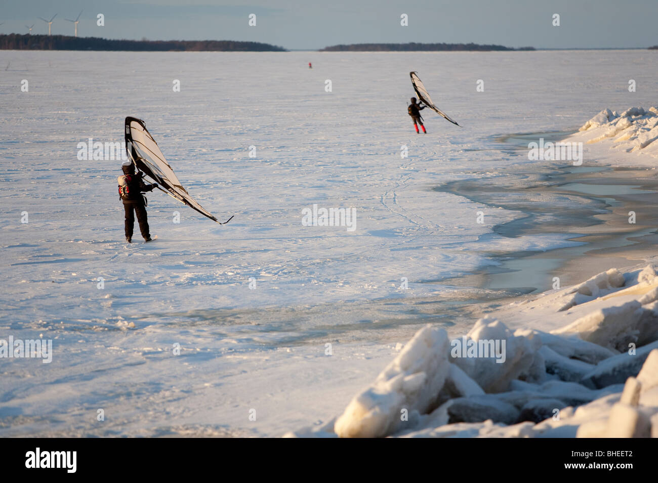 People skiing on sea ice at Winter , using a handheld  kitewing .  Baltic Sea , Gulf of Bothnia , Oulu , Finland Stock Photo