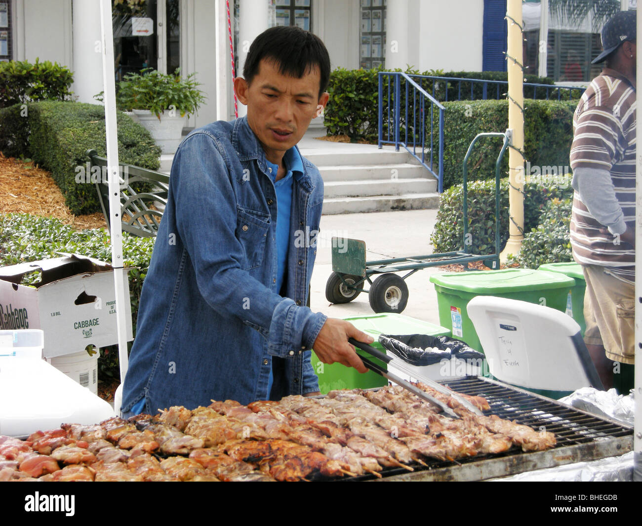 Oriental cook cooking BBQ food at an open air art show on Fifth Ave South Naples Florida USA Stock Photo