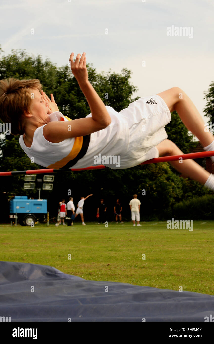 Boy high jumping at school sports lesson Stock Photo