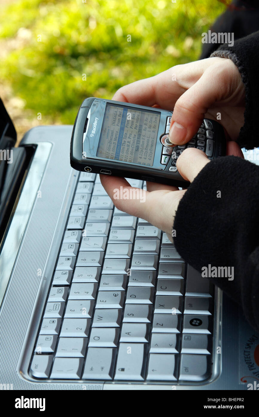 Woman hands holding a palmtop over a laptop's keyboard. Stock Photo