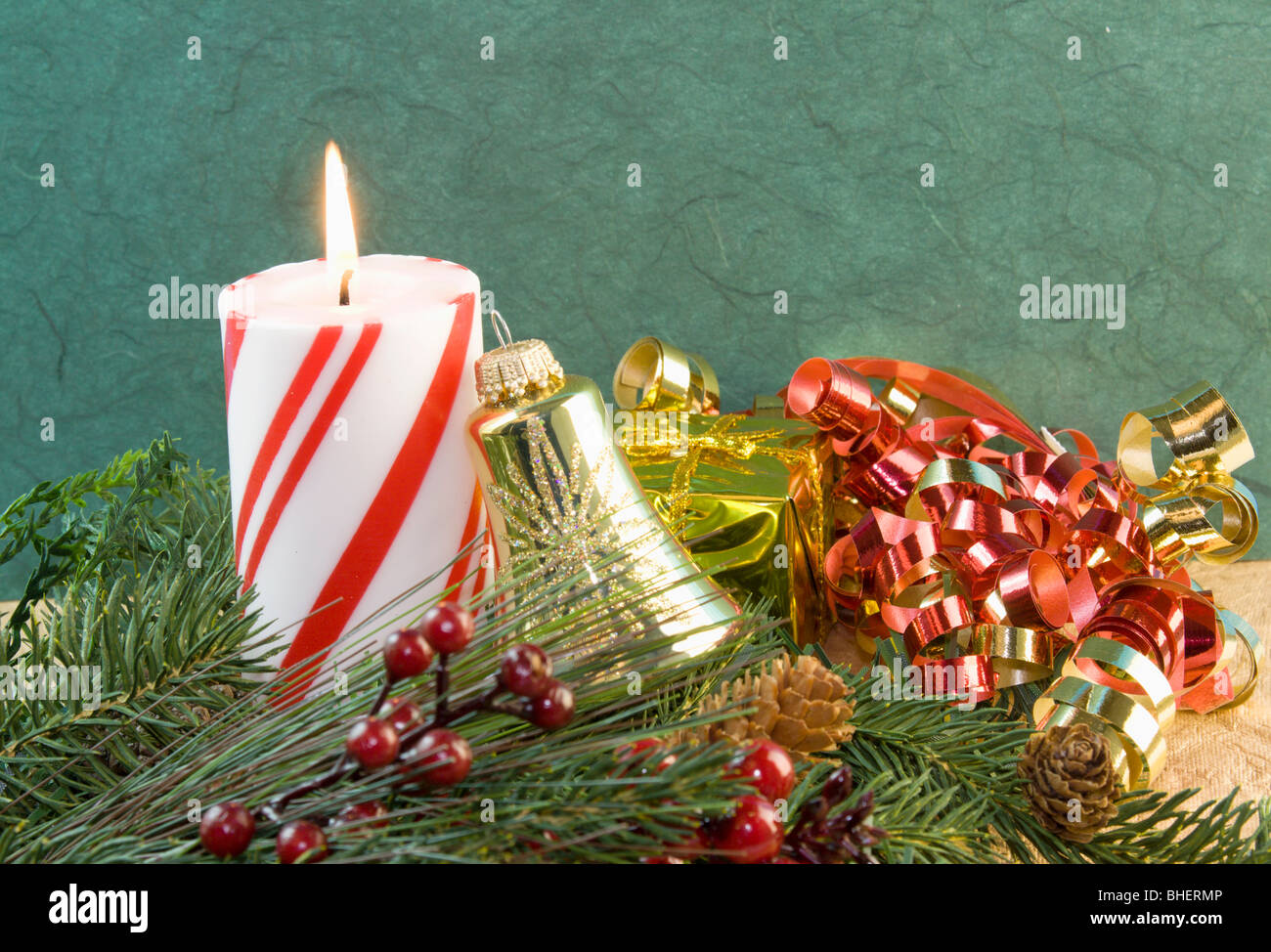 red and white striped Christmas candle with gold bell ornament and red curly ribbon Stock Photo