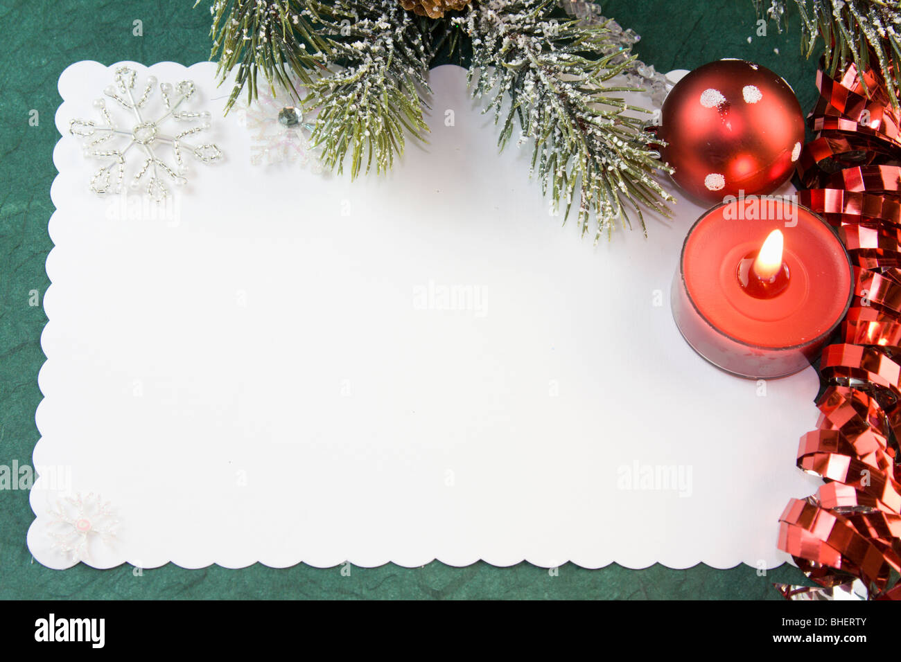 blank Christmas card with red tea light candle, curly ribbon, bauble and copyspace Stock Photo
