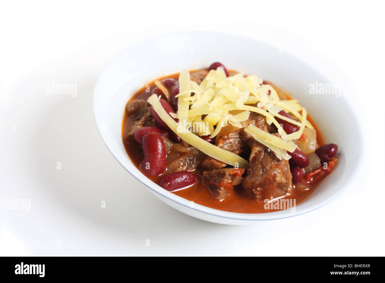 A bowl of beef chili, chilli con carne, topped with cheese, over white with a light shadow Stock Photo