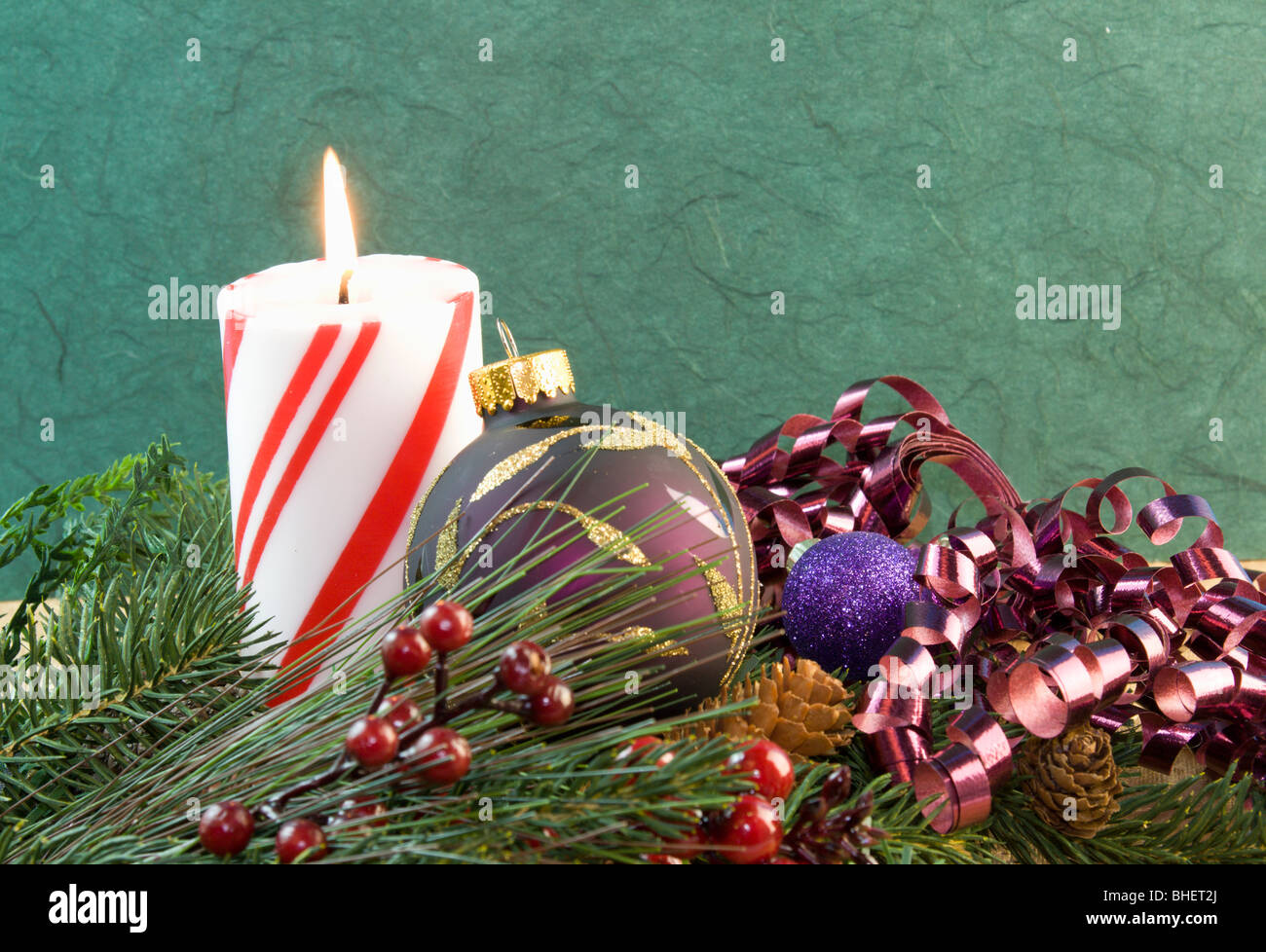 red and white striped Christmas candle with purple bauble and curly ribbon Stock Photo