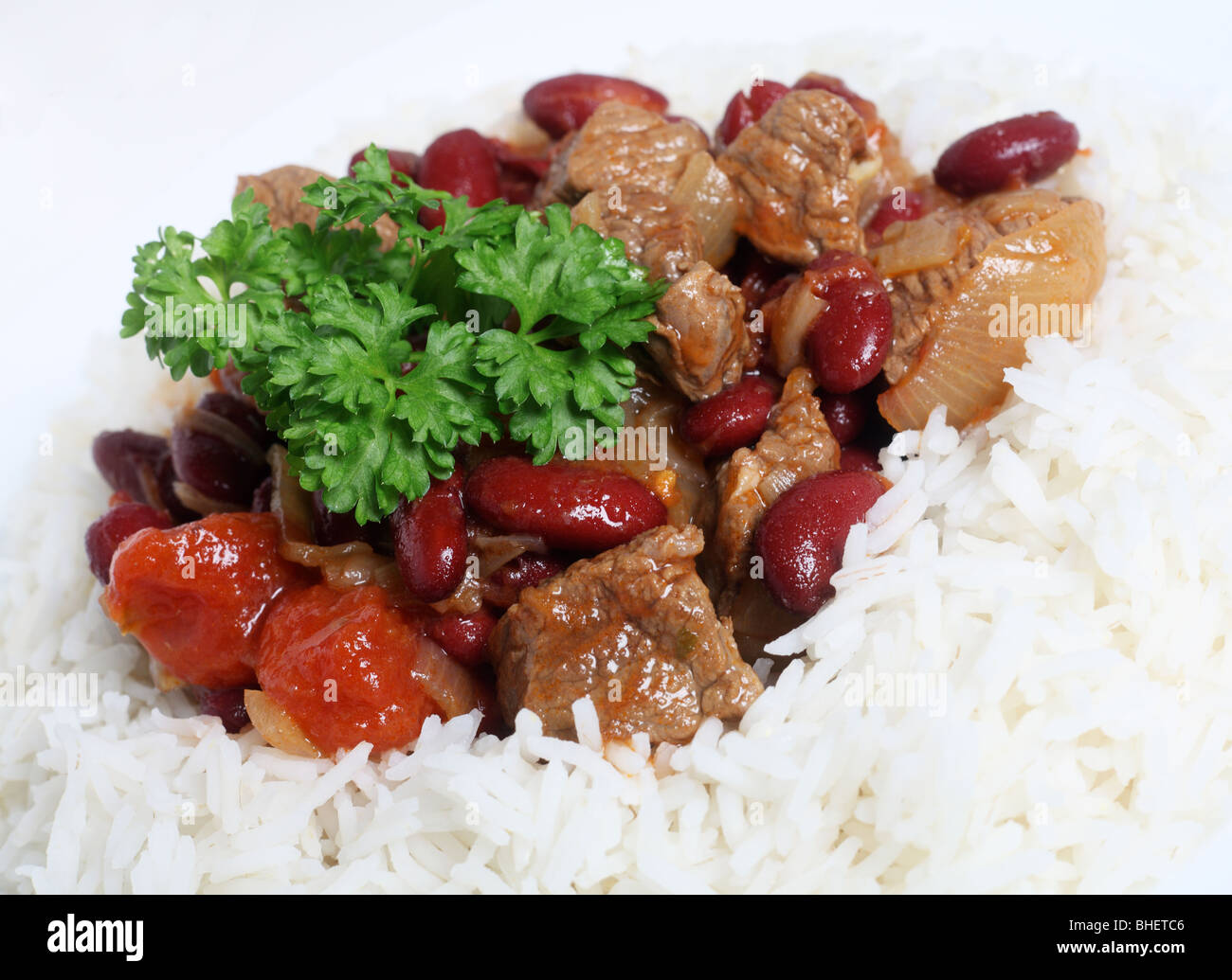 Macro shot of a chilli con carne beef stew with kidney beans on a bed of white basmati rice topped with a sprig of parsley Stock Photo