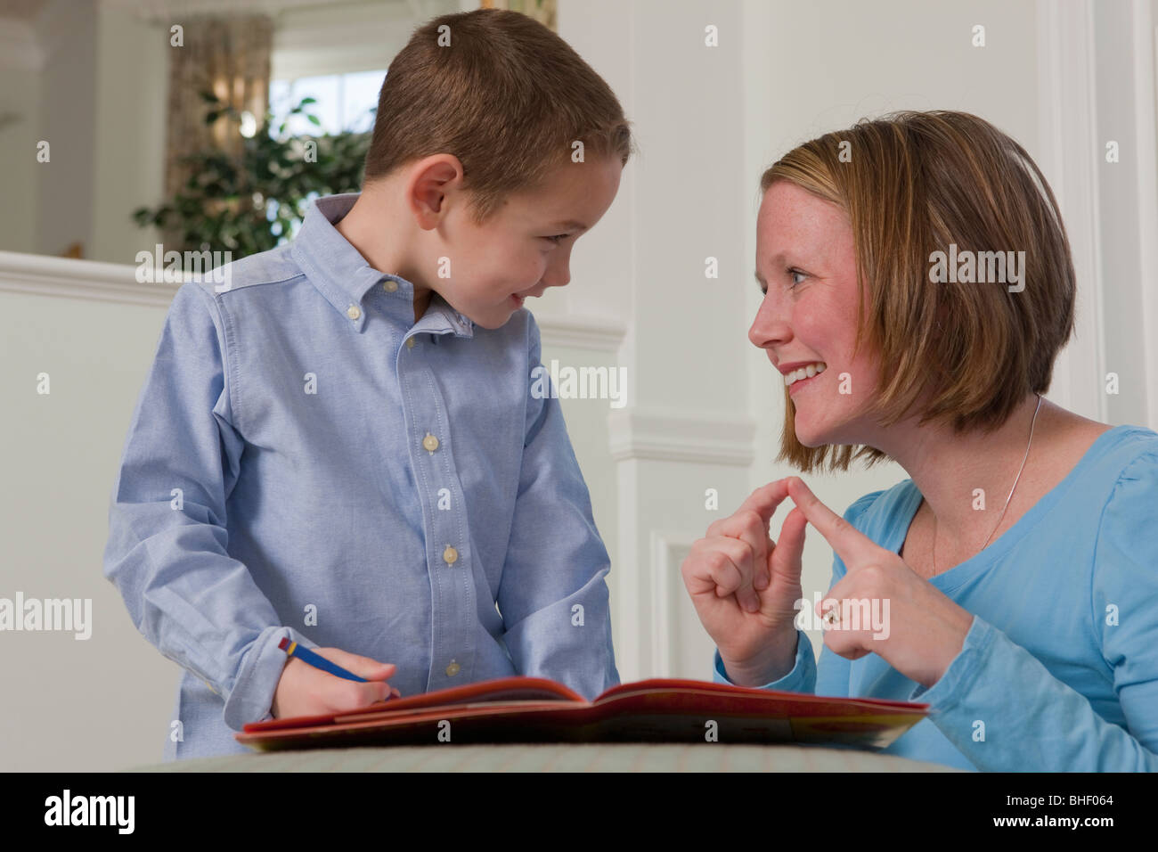 Woman signing the word 'Word' in American Sign Language while teaching her son Stock Photo