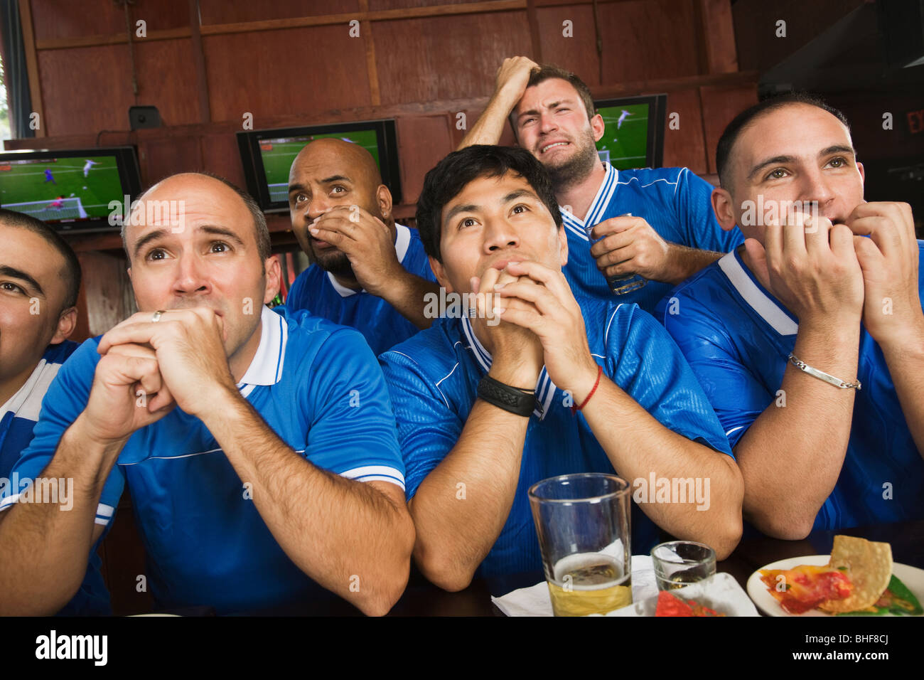 Worried teammates watching television in sports bar Stock Photo