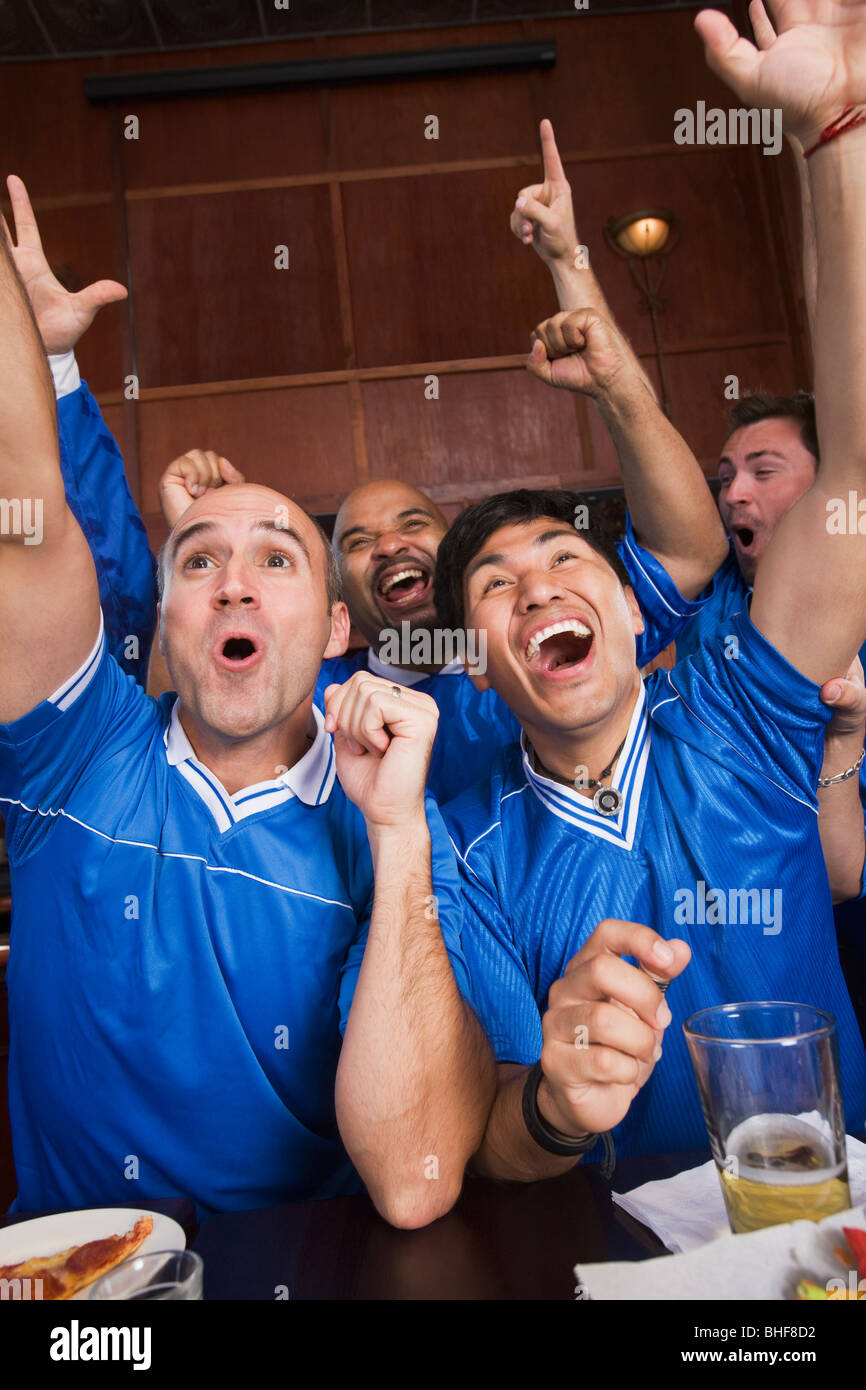 Cheering teammates watching television in sports bar Stock Photo