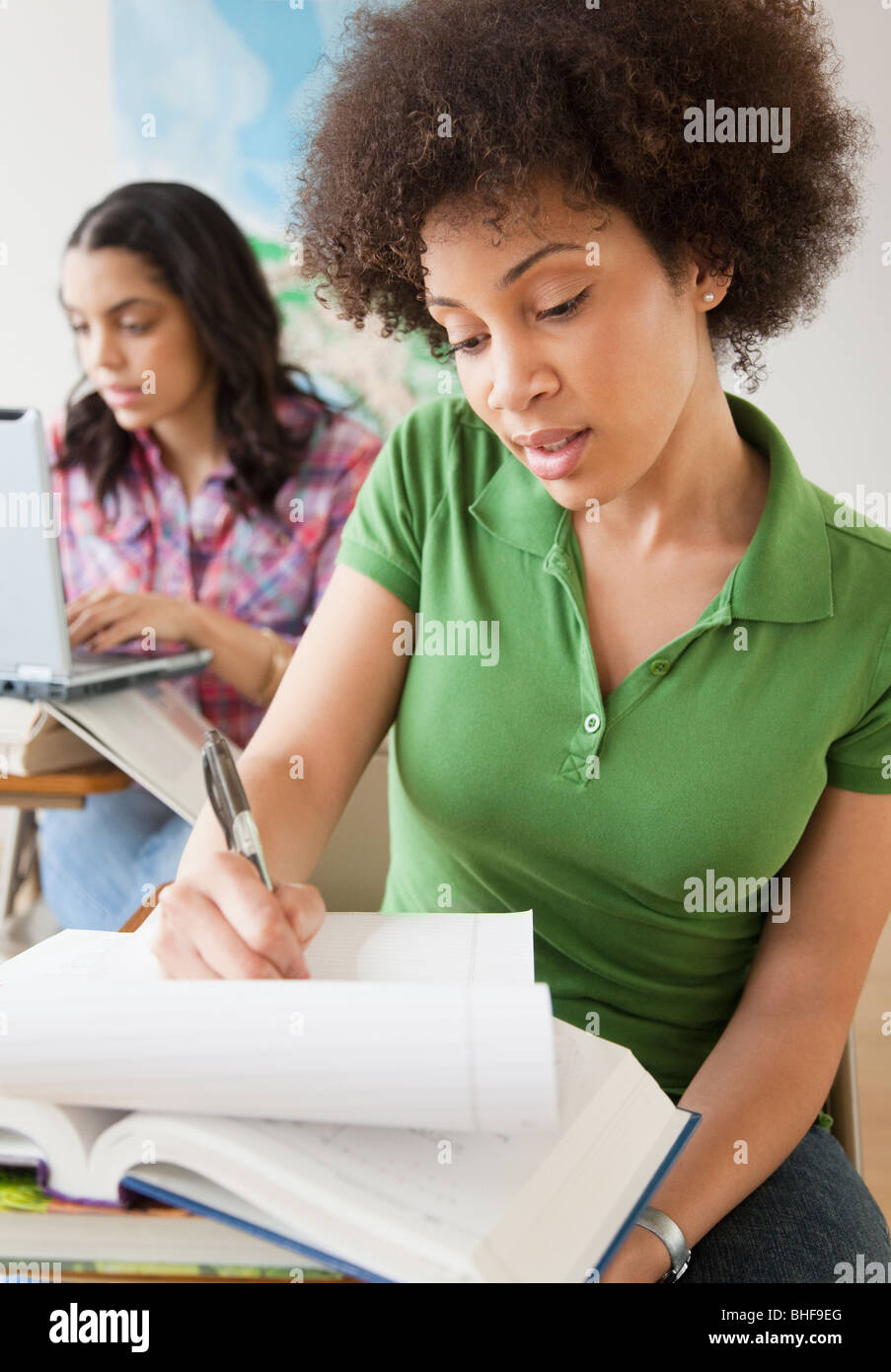 Mixed race woman taking notes in college classroom Stock Photo