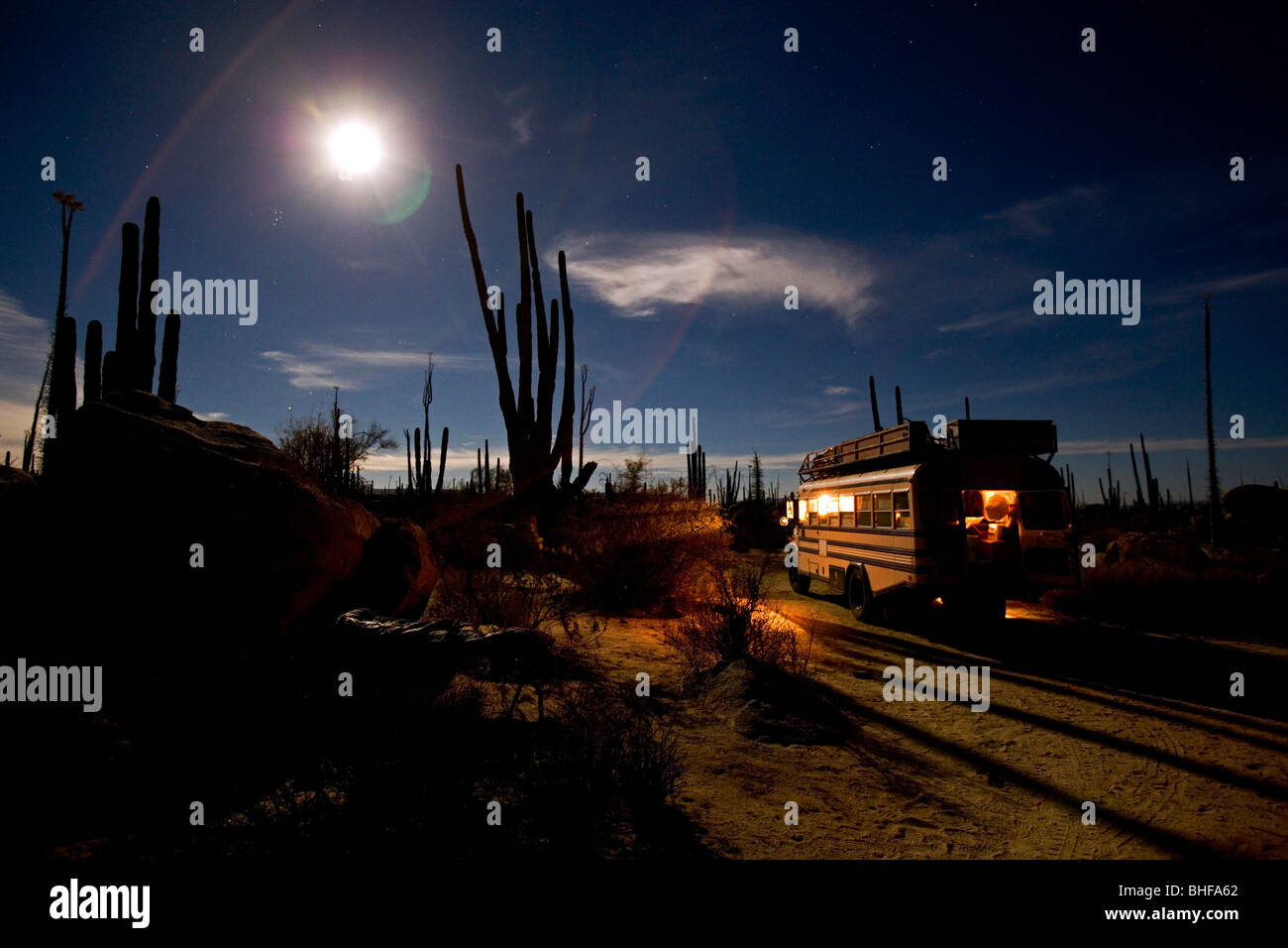 An American Schoolbus parked at night in the desert full of cactuses, fullmoon and starry sky, Catavina, Baja California Norte, Stock Photo