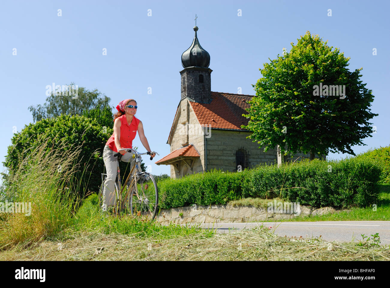 Female cyclist near chapel, Bad Koetzting, Bavarian Forest, Lower Bavaria, Bavaria, Germany Stock Photo
