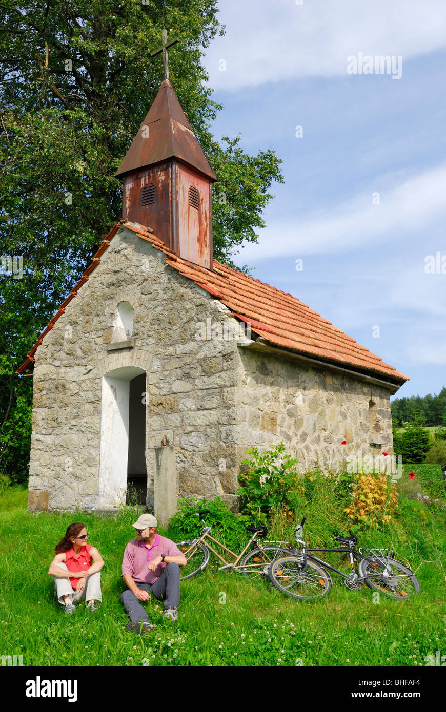 Cyclists resting near a chapel, Bad Koetzting, Bavarian Forest, Upper Palatinate, Bavaria, Germany Stock Photo