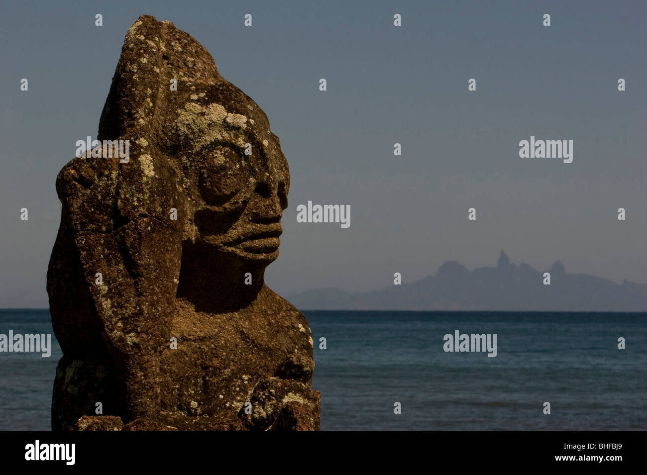 Tiki, weathered stone figure in front of Ua Pou island, Marquesas, Polynesia, Oceania Stock Photo