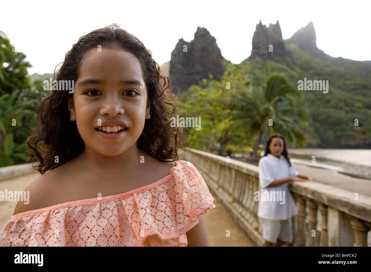 Two girls in front of peaks at Hatiheu, Nuku Hiva, Marquesas, Polynesia, Oceania Stock Photo