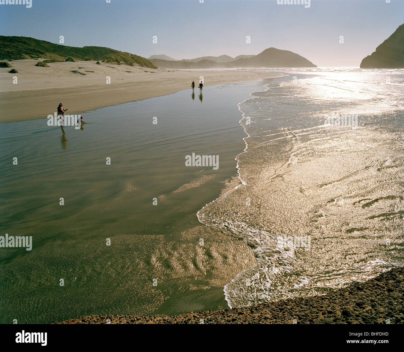People in the shallow water at Wharariki Beach, northwest coast, South Island, New Zealand Stock Photo