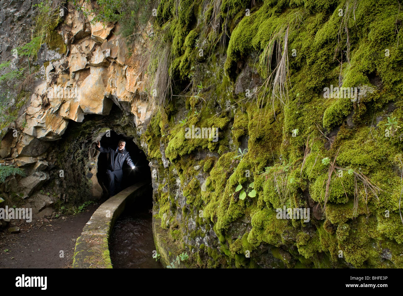 Man walking through a water channel and tunnel, moss, Galeria de agua, Fuentes Marcos y Cordero, natural preserve, Parque Natura Stock Photo