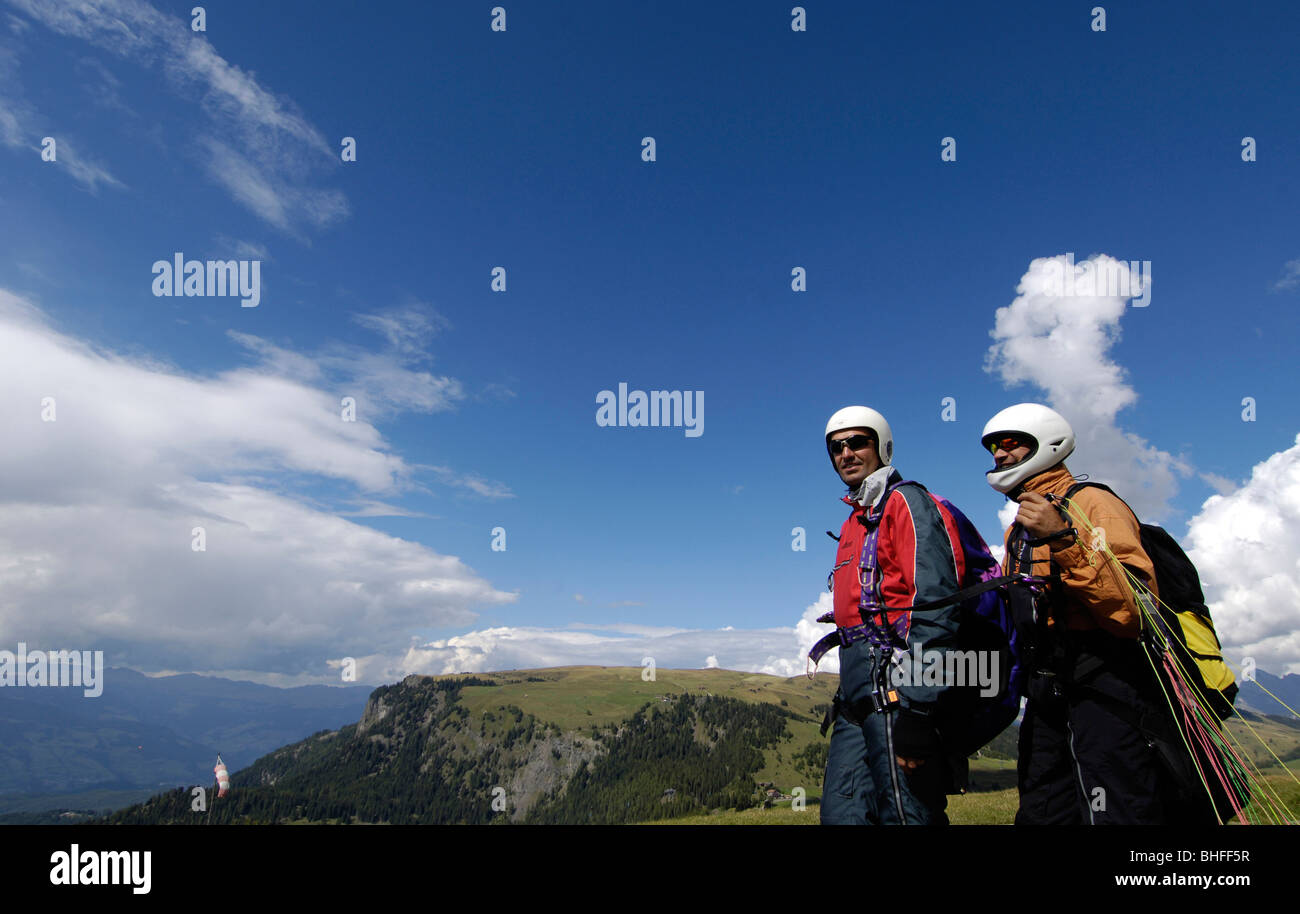 Two men wearing helmets in front of mountains and blue sky, Alpe di Siusi, Valle Isarco, South Tyrol, Italy, Europe Stock Photo
