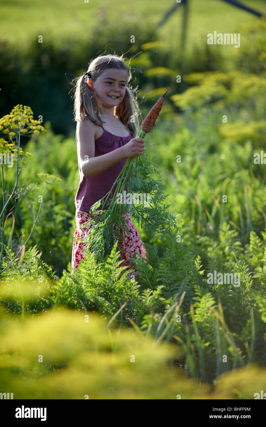 Girl (8-9 years) holding carrot, Lower Saxony, Germany Stock Photo