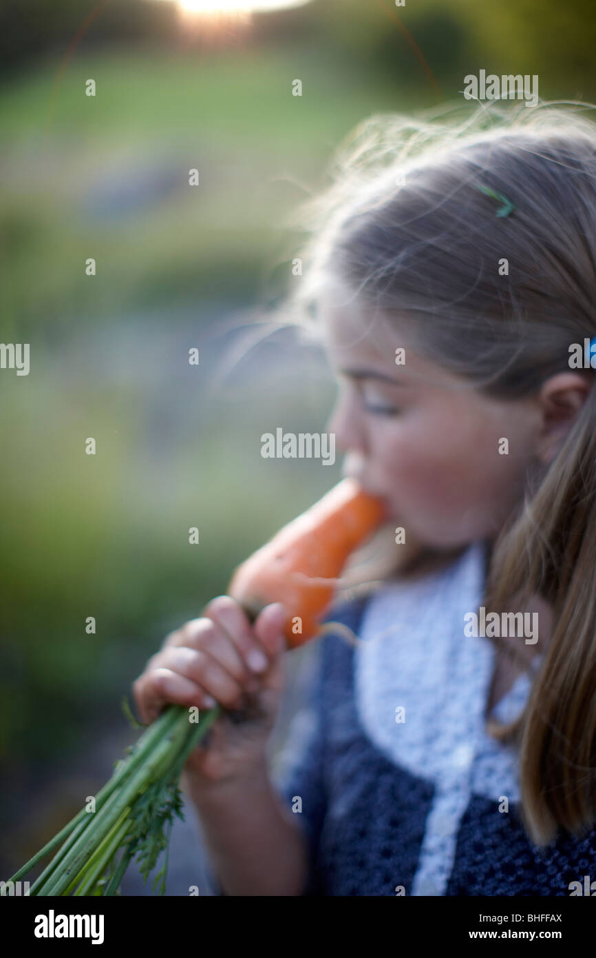 Girl (8-9 years) eating a carrot, Lower Saxony, Germany Stock Photo