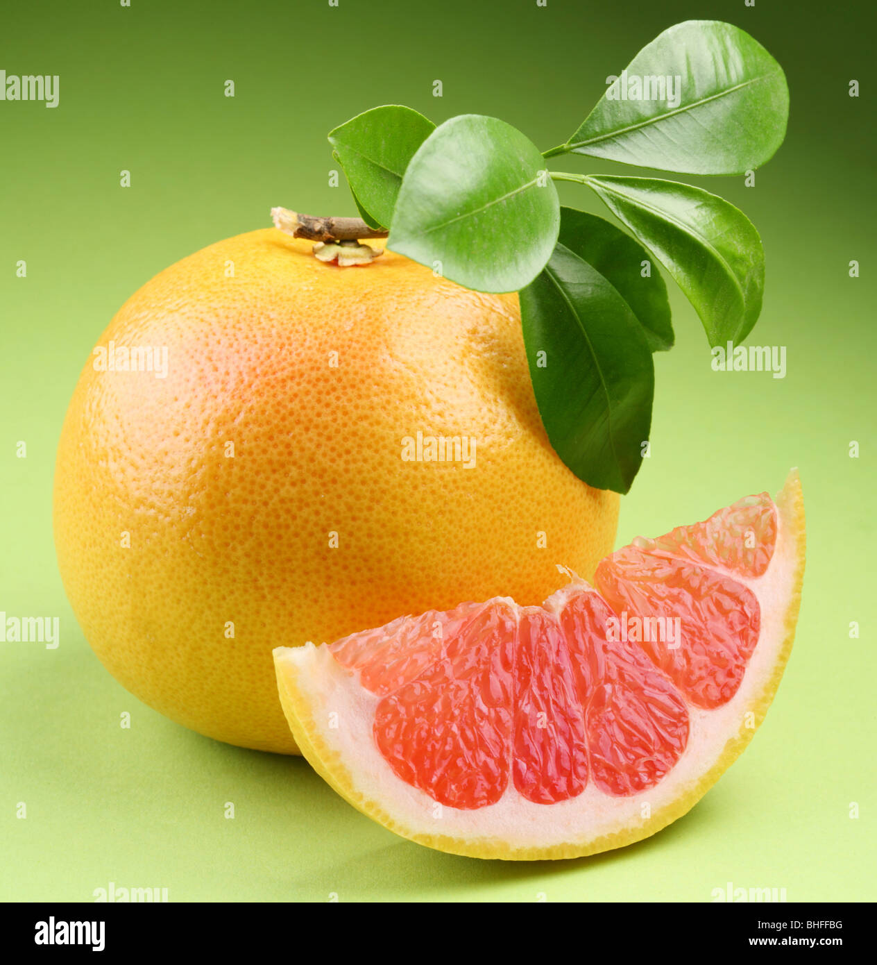 Ripe grapefruit with segment on a green background Stock Photo