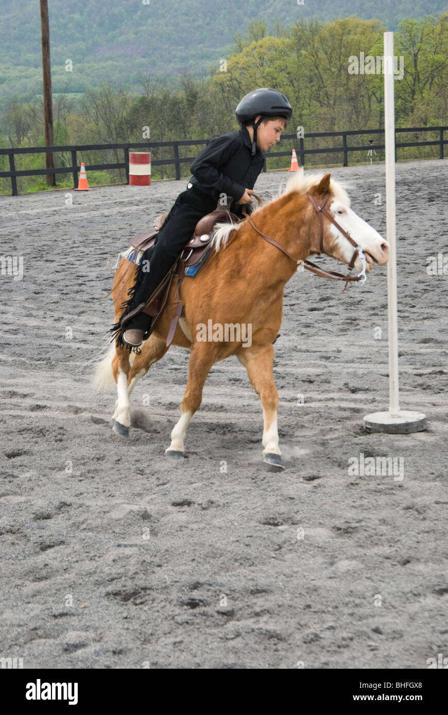 Picture of young boy and pony running the pole bending course at a horse show. Stock Photo
