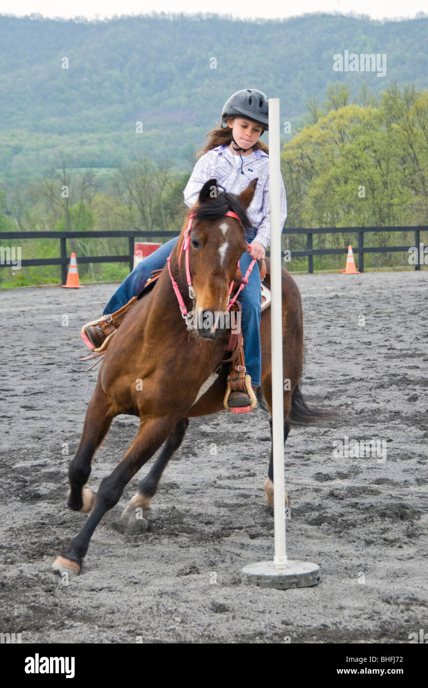 Stock photo of young girl and horse turning the last pole in a horse show competition. Stock Photo
