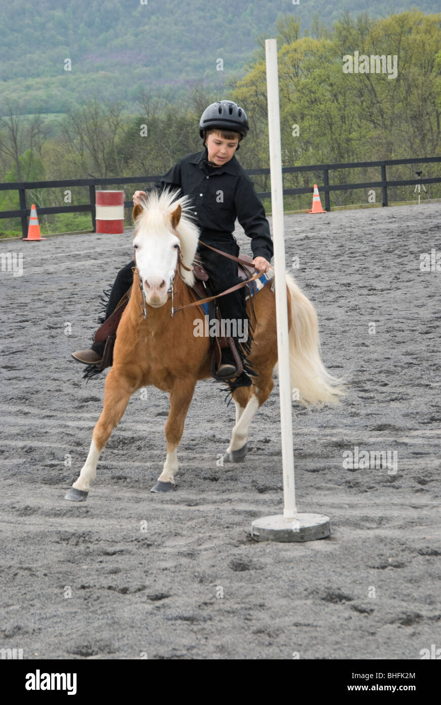 Picture of young boy and pony running the pole bending course at a horse show. Stock Photo