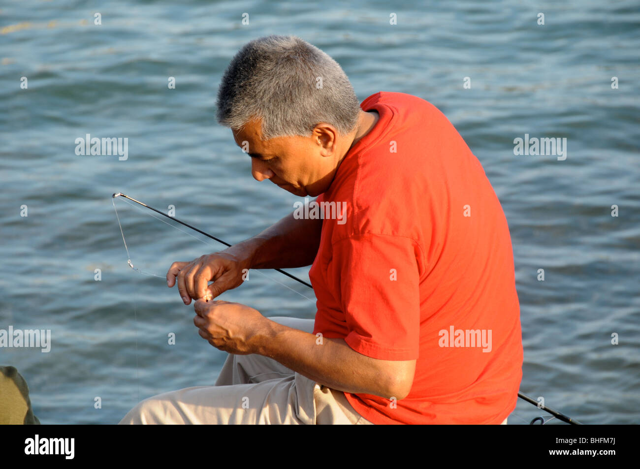 The fisherman ties the hook to the line. Tie the fishing hook to the fishing  line. Fish hook on the palm. Holding a hook Stock Photo - Alamy