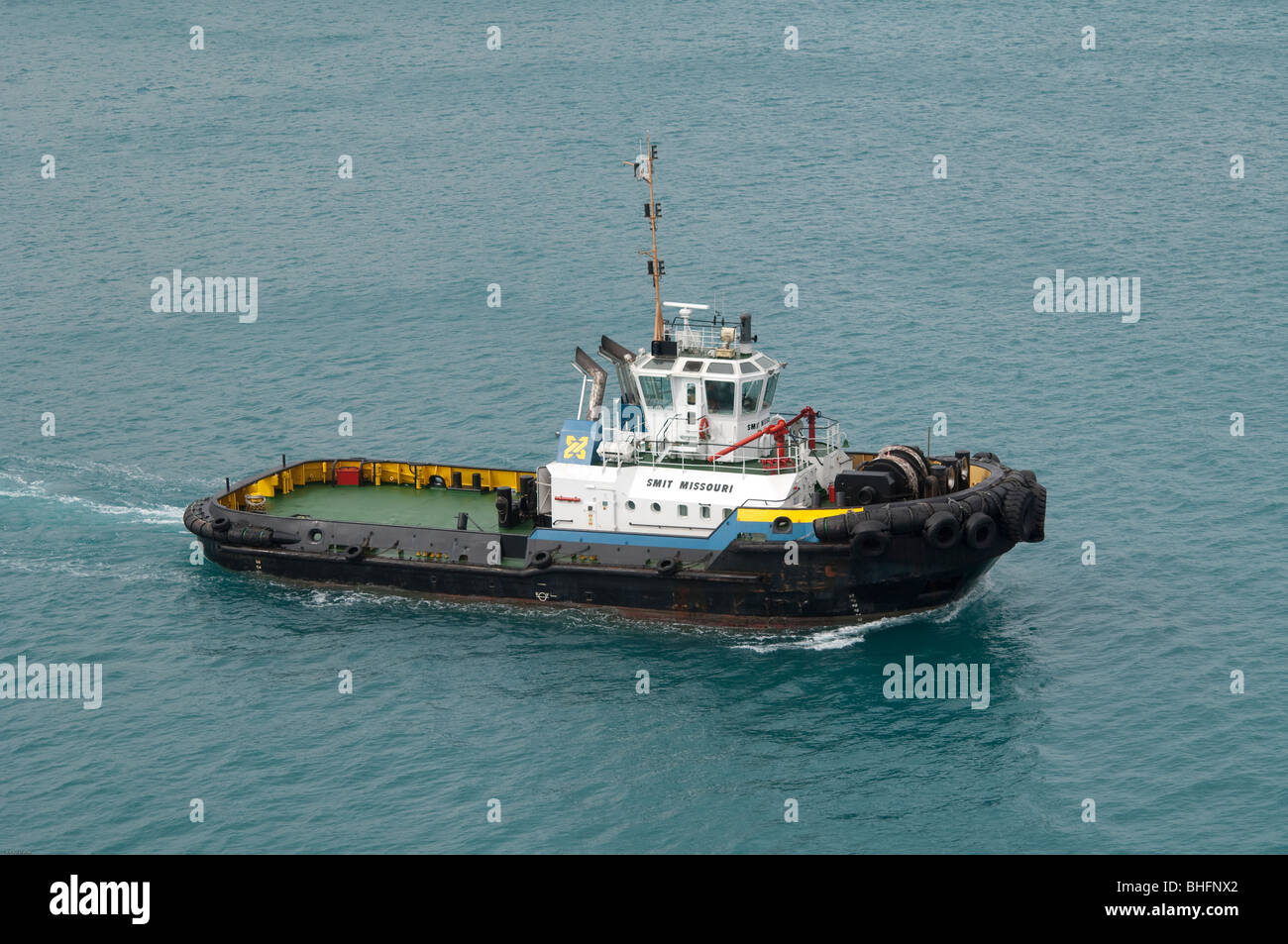 The 'Smit Missouri' tug boat motors across the harbour to provide assistance to another ocean going cargo ship. Stock Photo