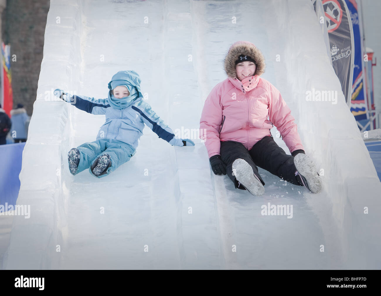 A woman and her daughter ride an ice slide at the Quebec Winter Carnival (Carnaval de Quebec) in Quebec city. Stock Photo