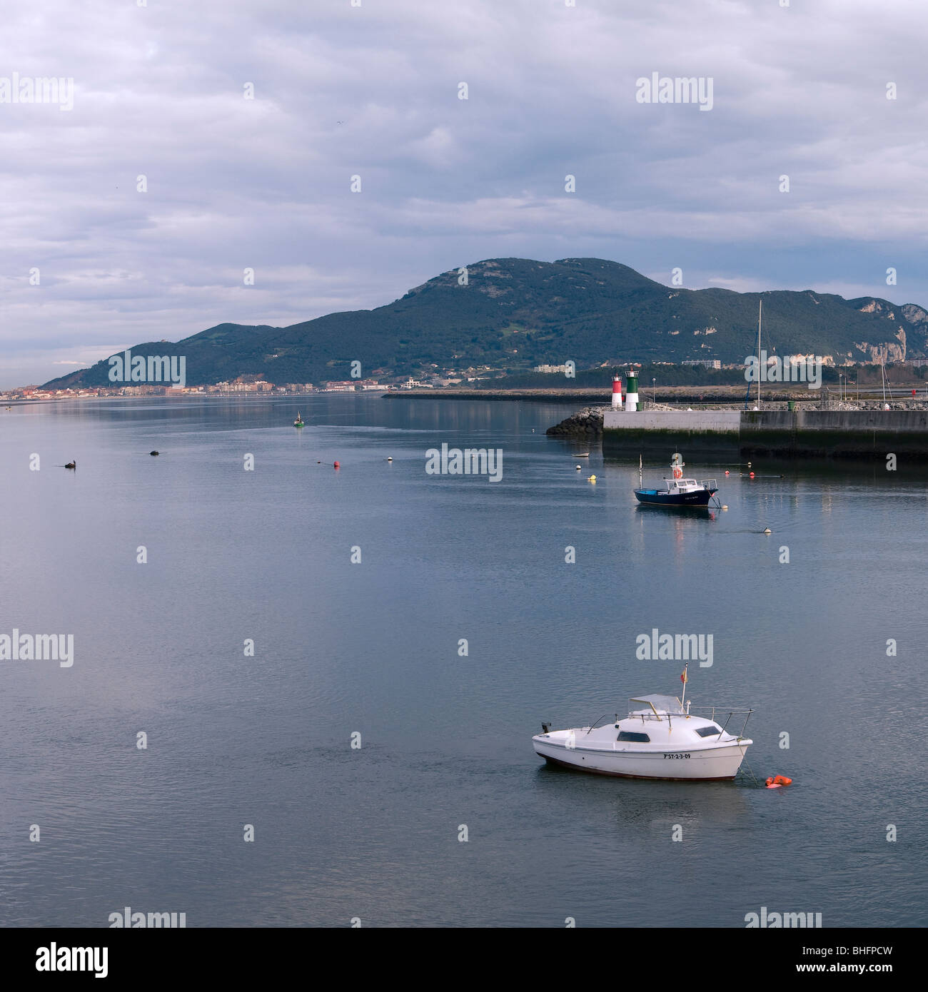 seascape with two small yachts and a mountain in the background at the entrance to the port of Colindres, Cantabria, Spain Stock Photo