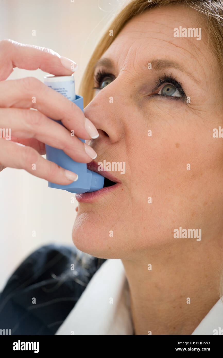 Woman using bronchial dilator to relieve asthma symptoms. Stock Photo