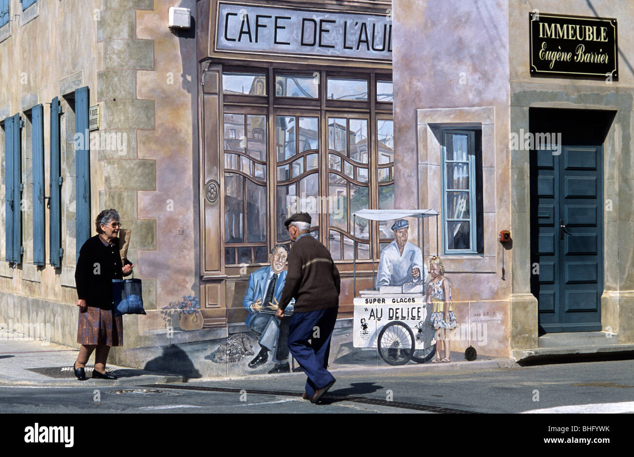 Old or Retired French Couple Meeting in Street Outside 'Cafe de l'Aude' Wall Painting, Puichéric, Minervois, Aude, France Stock Photo