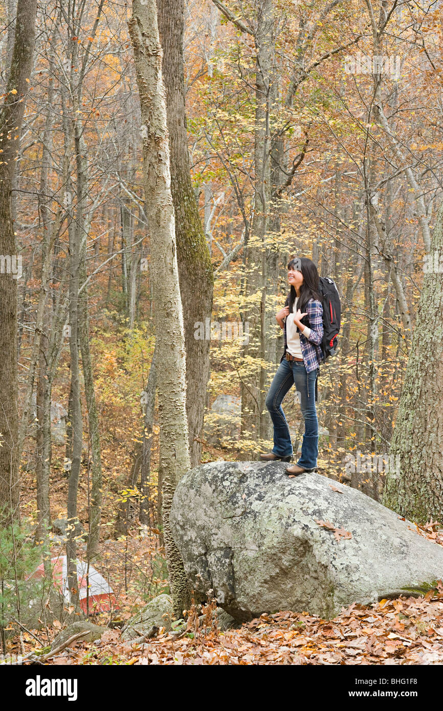 Young woman standing on stone in forest Stock Photo