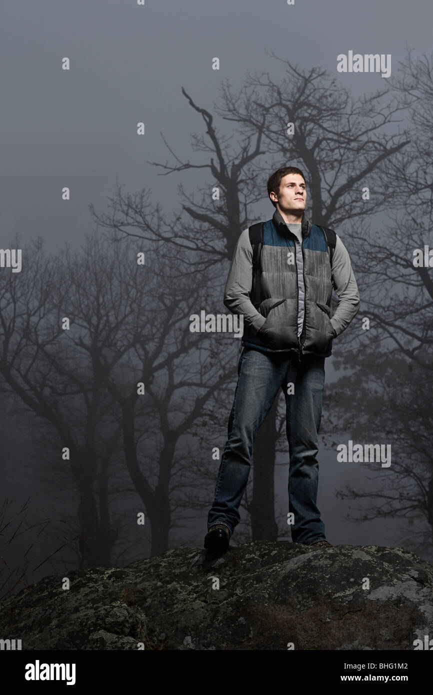 Portrait of a male hiker standing on a forest boulder Stock Photo
