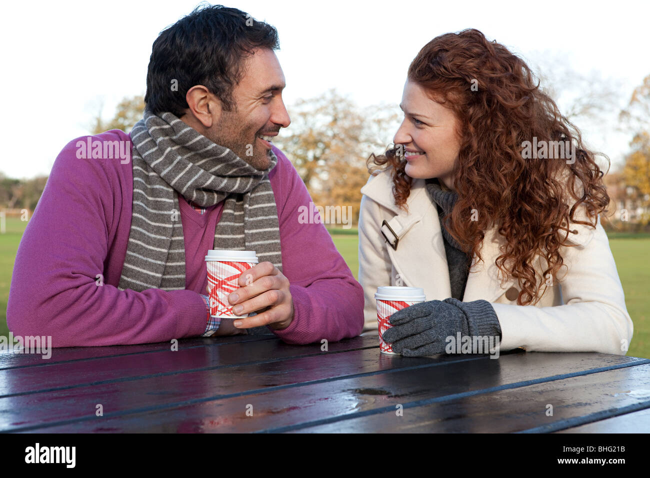 A couple face to face sitting at a park table Stock Photo - Alamy