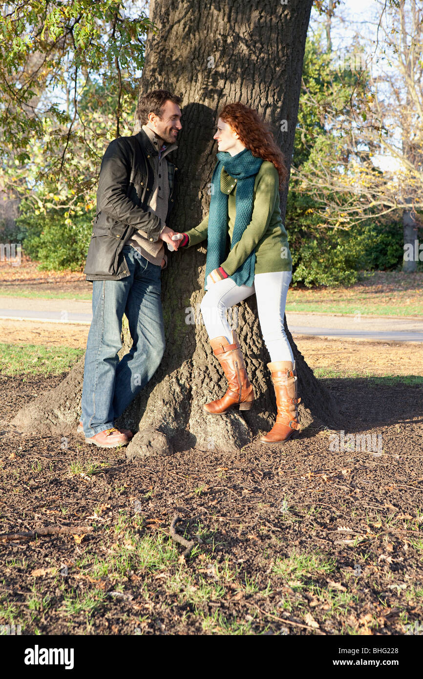 A couple stand face to face next to a tree Stock Photo