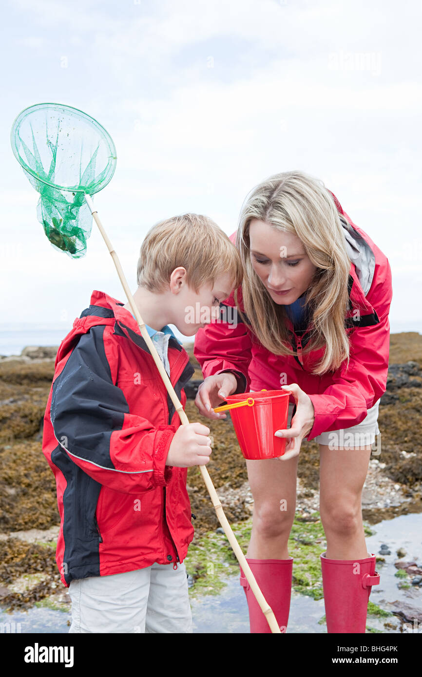 Mother and son looking in rock pool Stock Photo