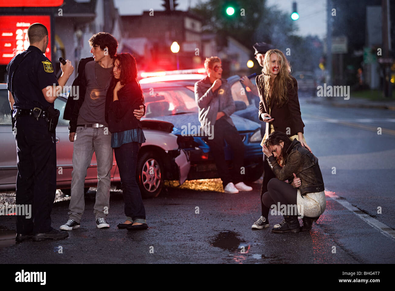 Young people and police officer at scene of car crash Stock Photo