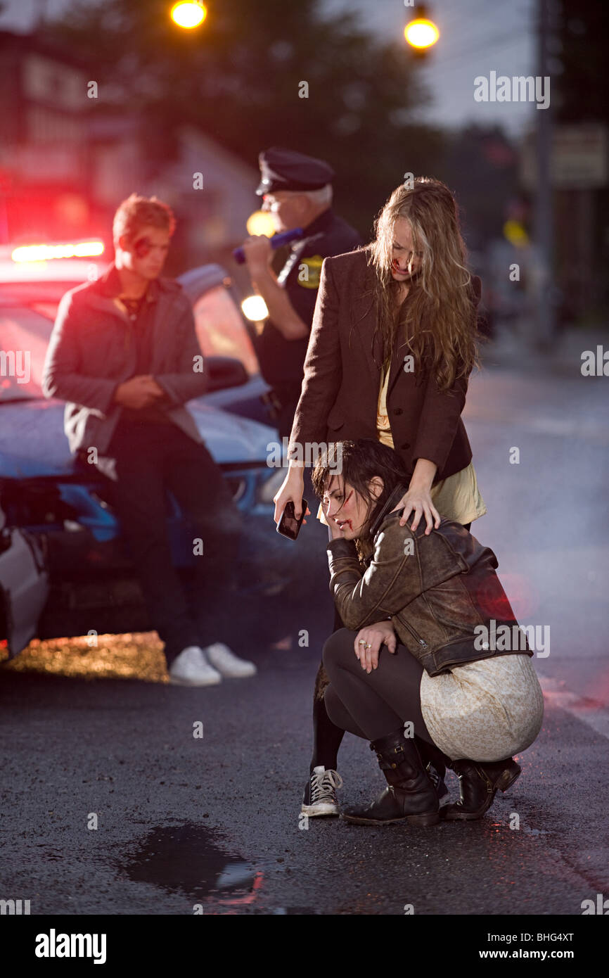 Young people and police officer at scene of car crash Stock Photo