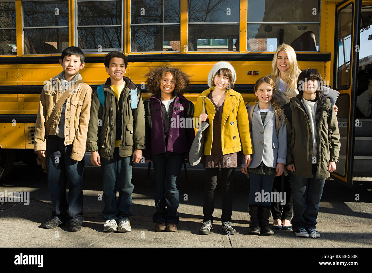 Children and teacher by school bus Stock Photo