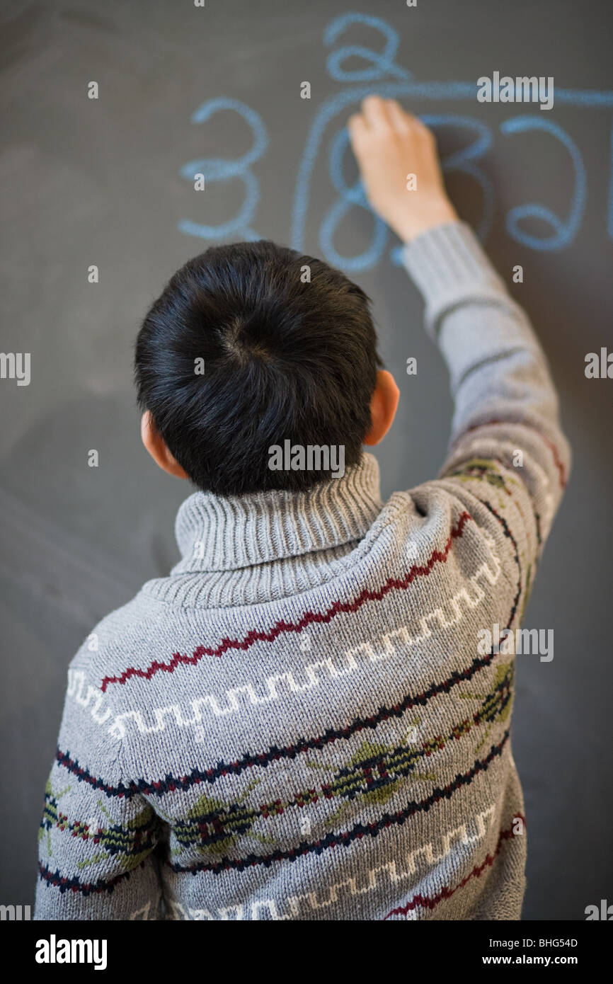 Boy writing on blackboard Stock Photo