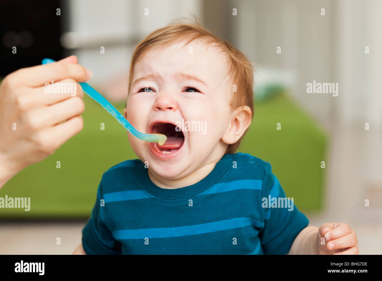 crying baby sitting in chair being fed Stock Photo Alamy