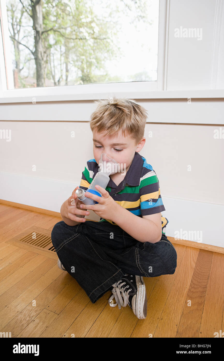 Boy using asthma inhaler with spacer Stock Photo