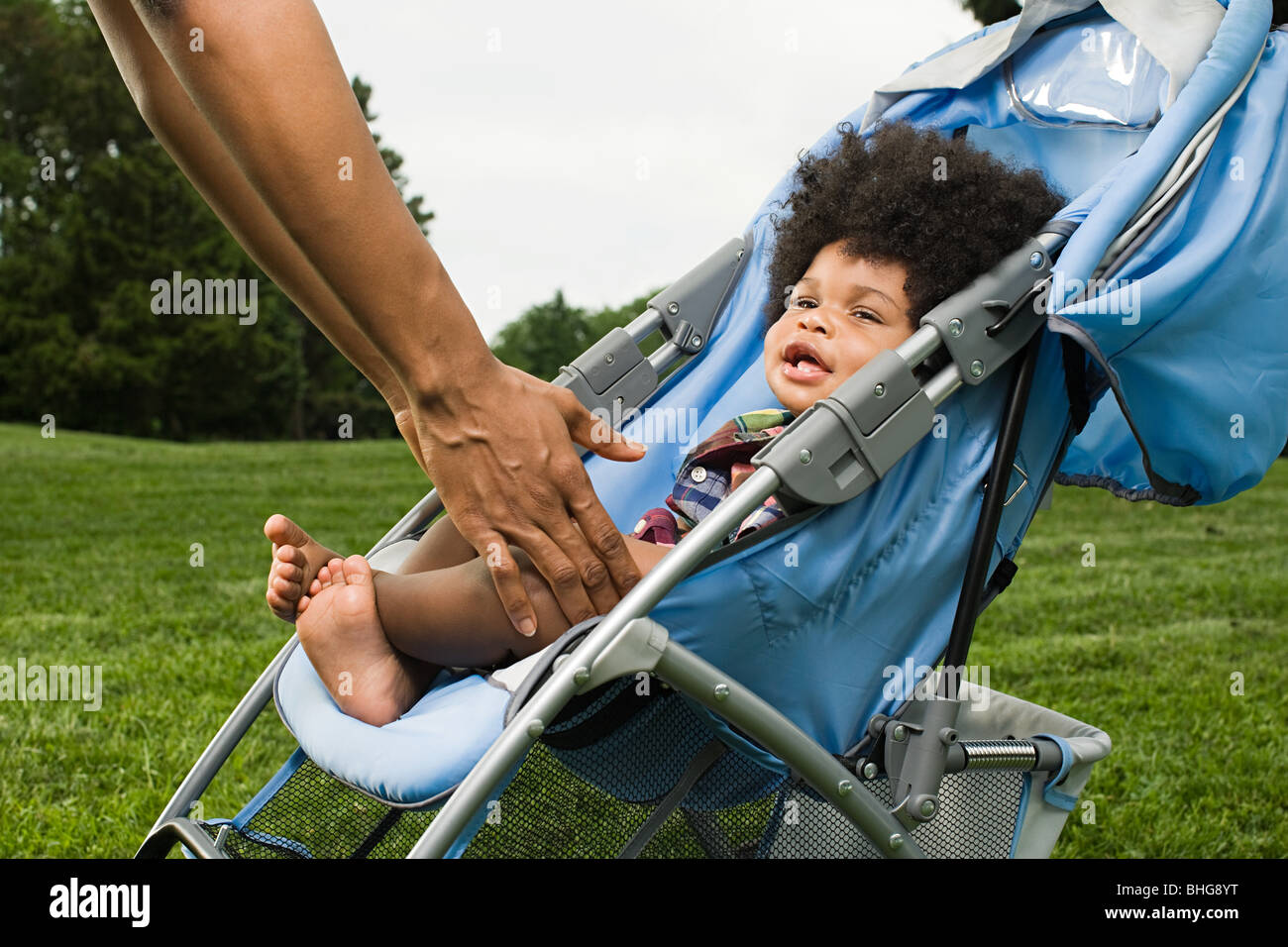 Parent reaching for baby in push chair Stock Photo