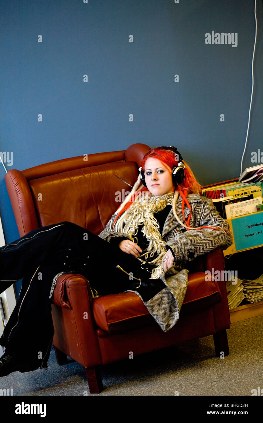 Teenage girl with earphones lying in an armchair, Sweden. Stock Photo