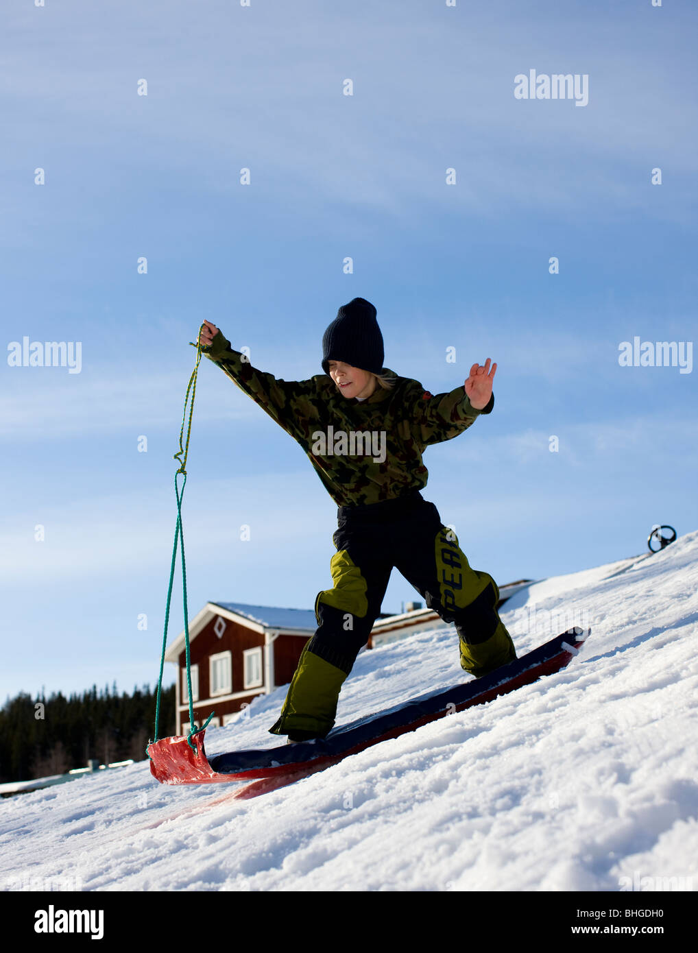 Boy gliding down a slope on a mattress, Sweden. Stock Photo