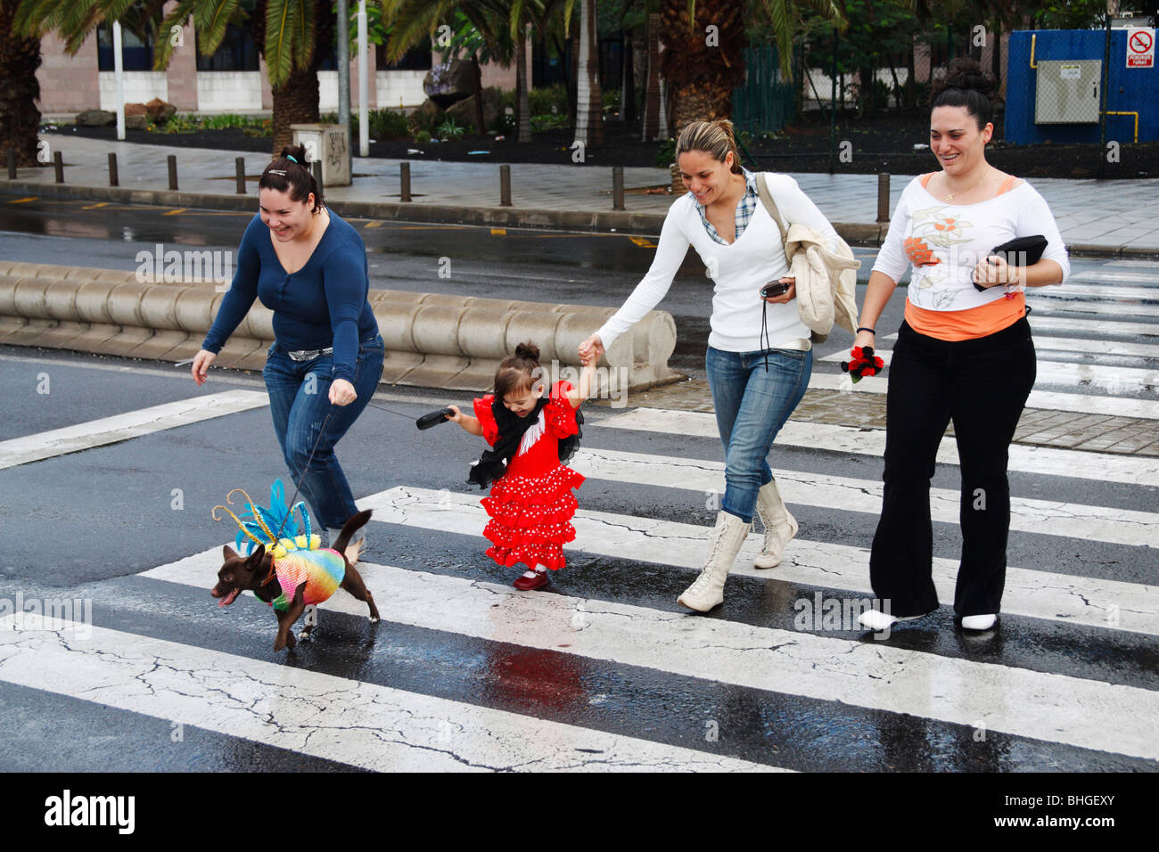 Young Spanish girl in flamenco dress with dog on lead in fancy dress on ther way to carnival in Las Palmas on Gran Canaria. Stock Photo