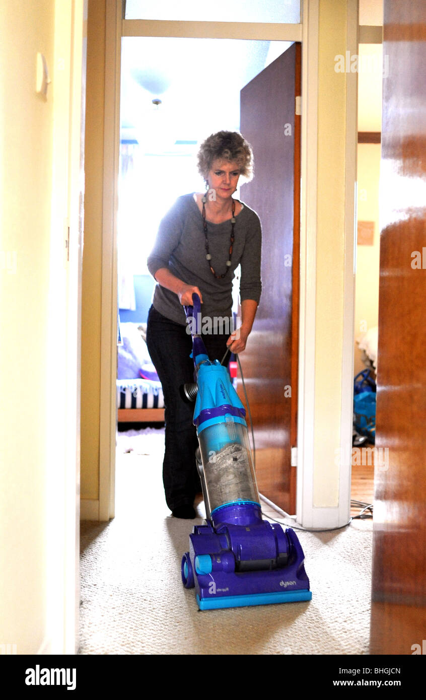 Woman using a Dyson Hoover to clean carpet in home Stock Photo