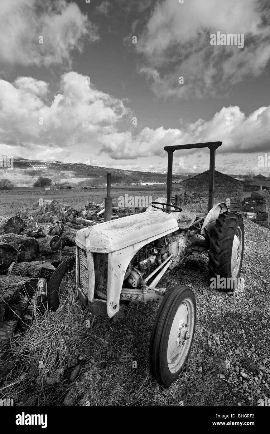 An old tractor sits before fields surrounding Hawes and Gayle in Wensleydale, Yorkshire Dales Stock Photo